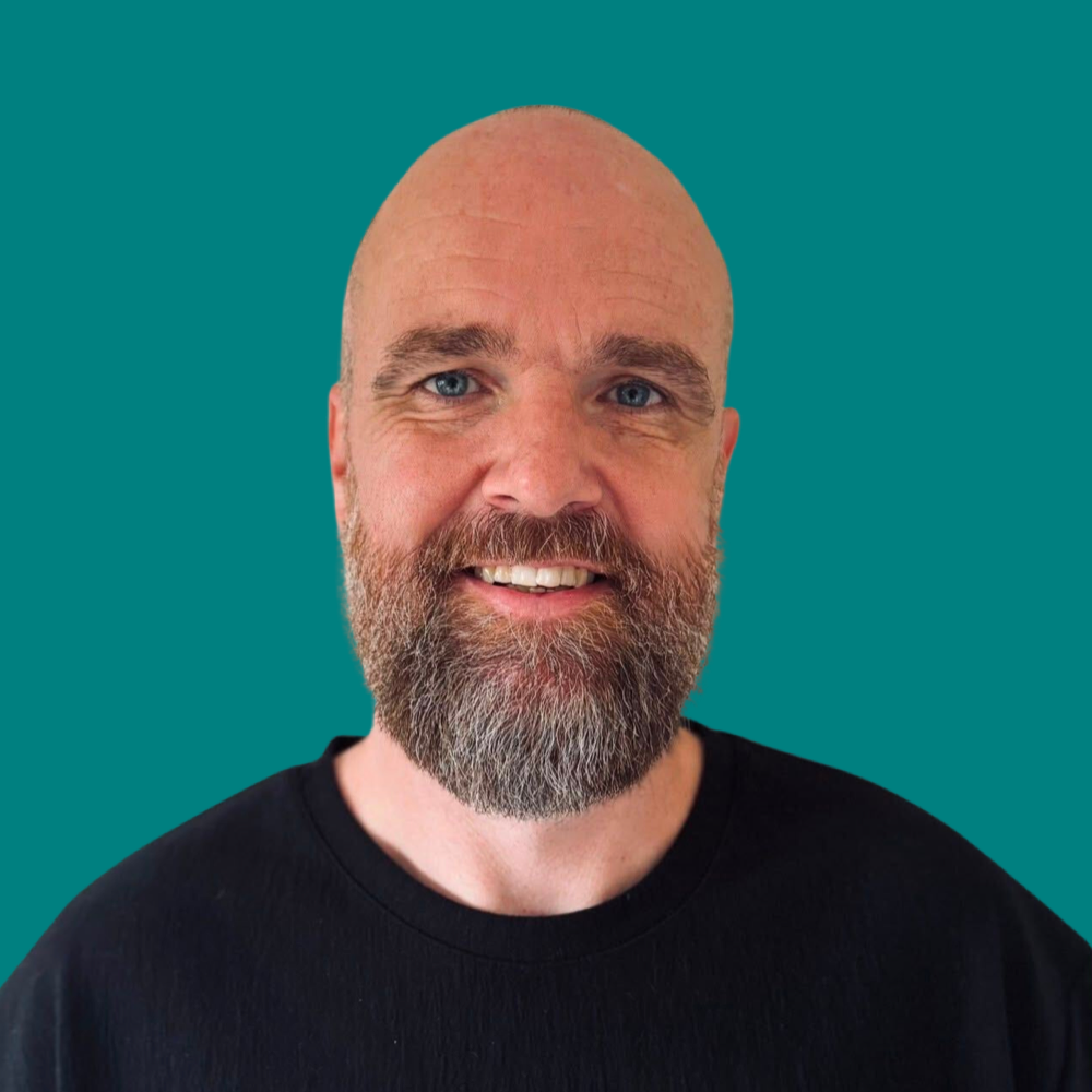 Smiling at the camera, with a beard.